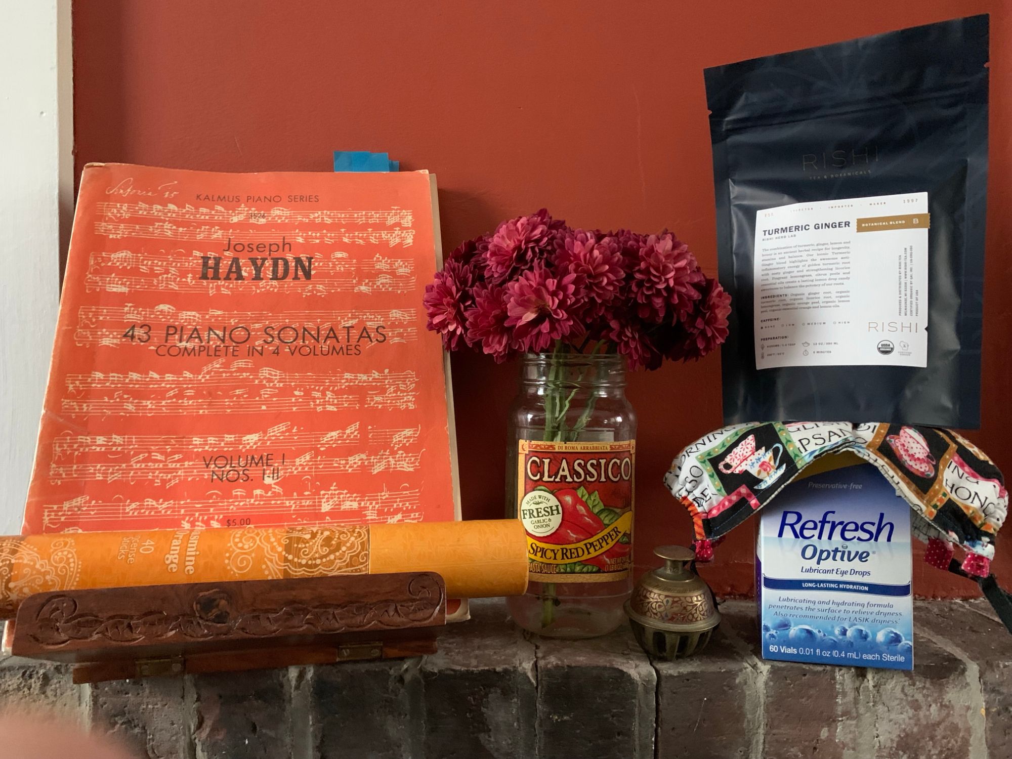 Tableaux of objects including Haydn Sonatas for Piano, red flowers, Refresh eye drops, ginger turmeric tea 