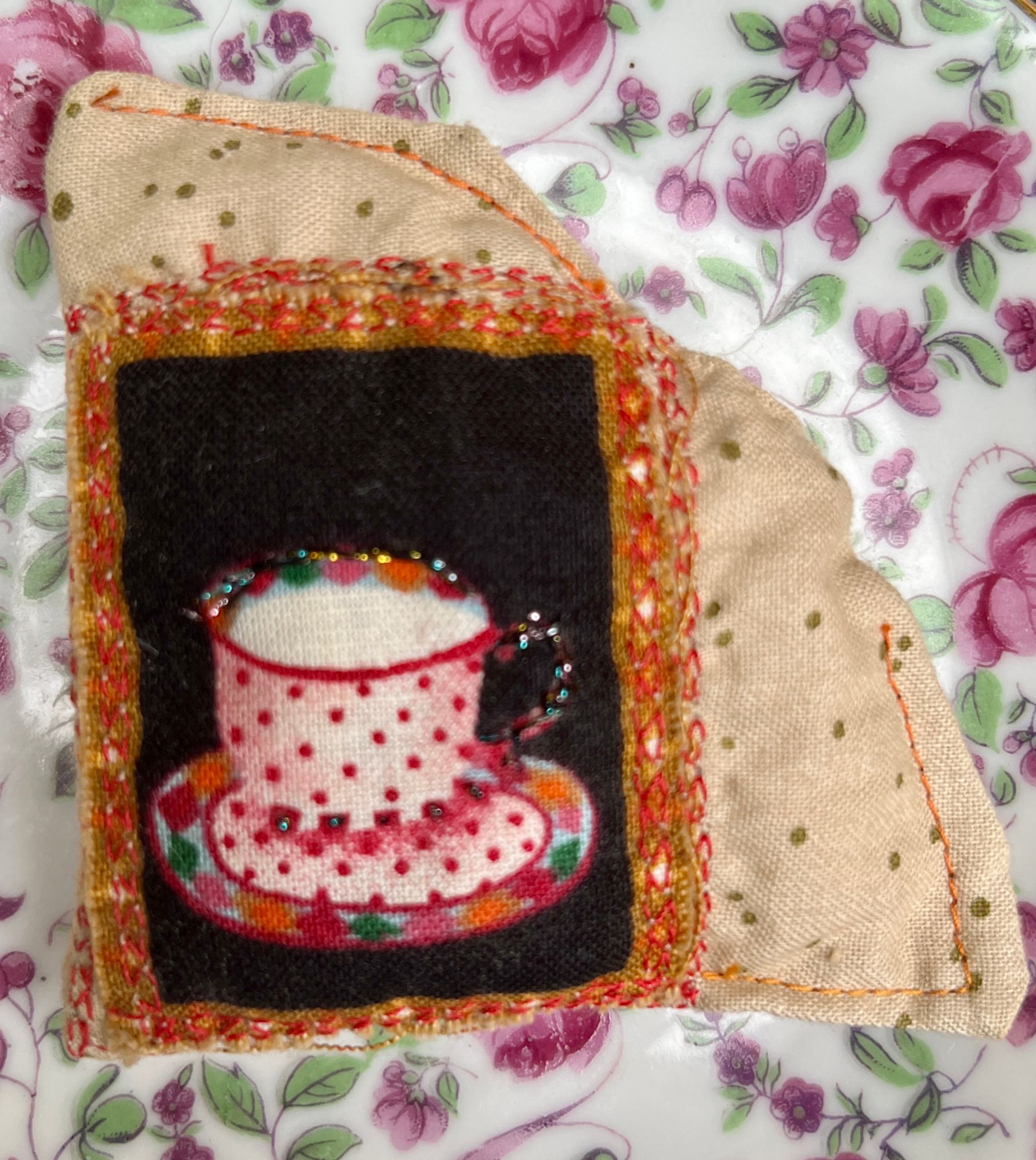 Pink teacup themed fabric piece with decorative stitching